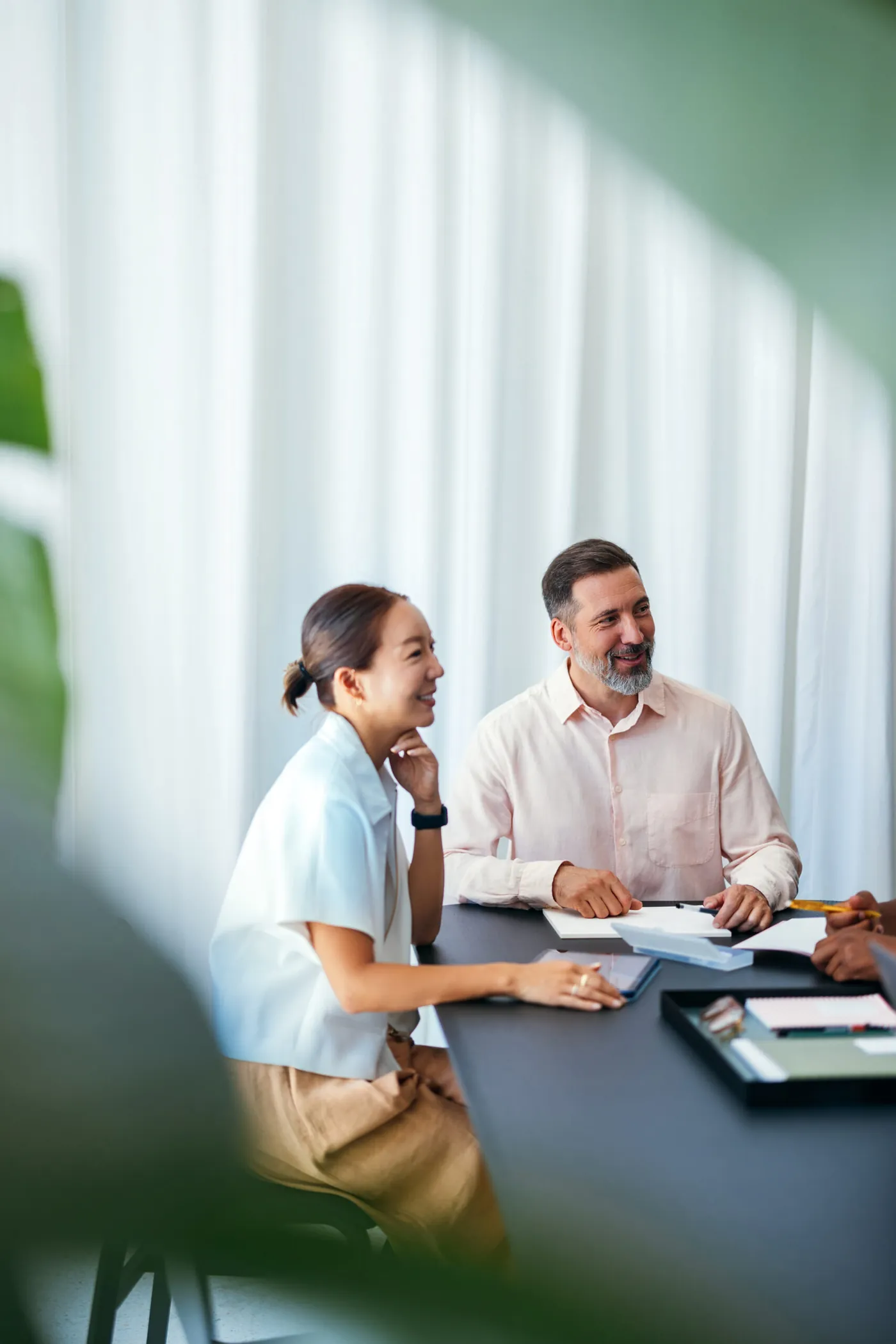 Two coworkers interacting during a workplace meeting, displaying teamwork and camaraderie in a professional setting with a bright, positive atmosphere.
